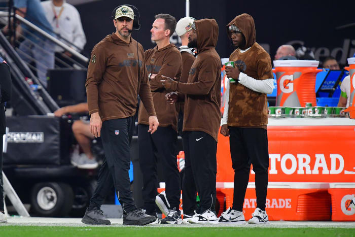 Aaron Rodgers walks along the sideline past a bunch of Jets staff